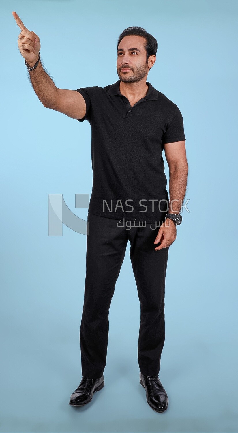 Photo Of a Handsome man Standing and pointing away, Smiling Man, Wearing Casual Clothes Posing In a Light Room Interior, Smiling At the Camera
