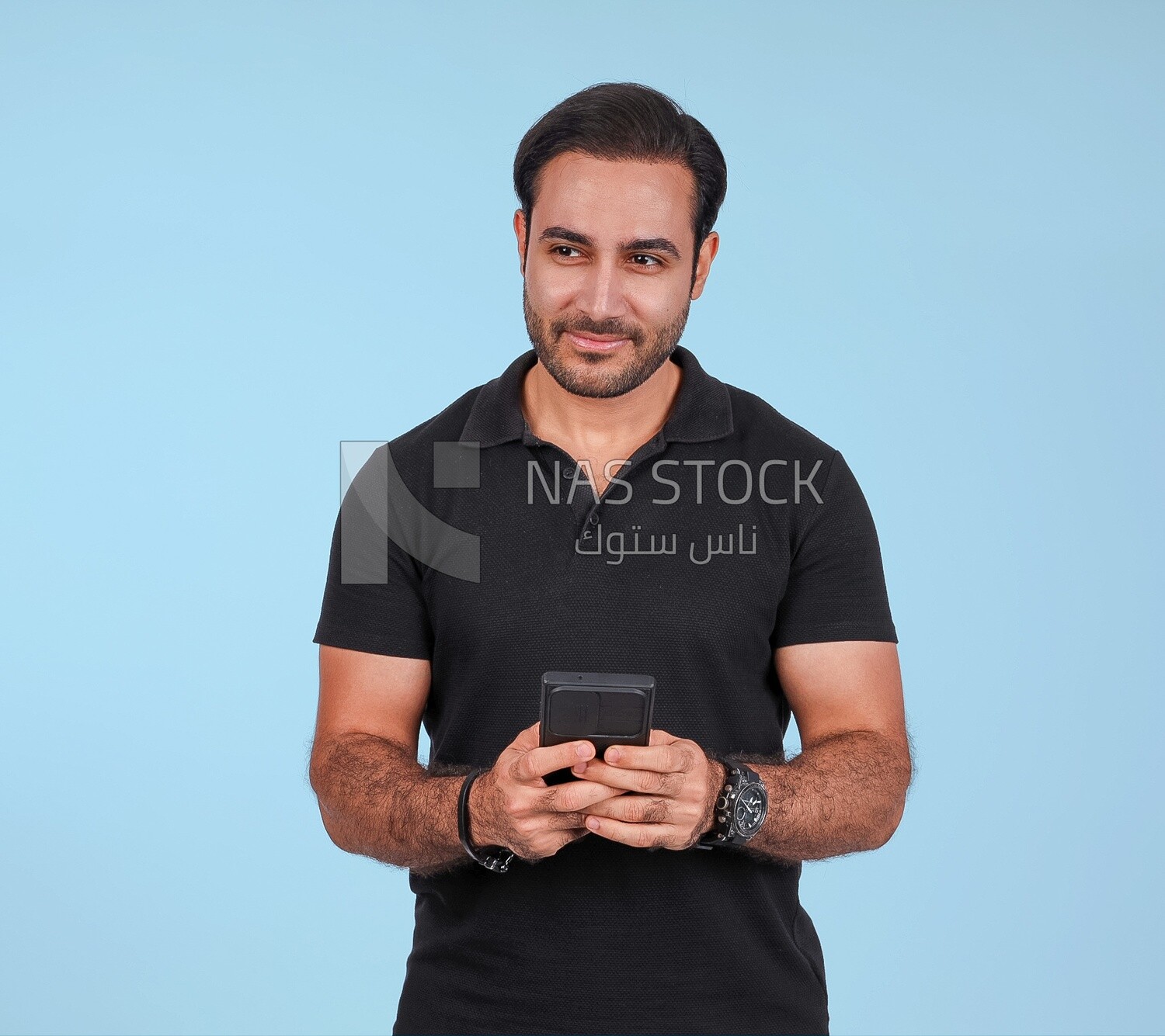 Photo Of a Handsome man Standing and holding his mobile, Smiling Man, Wearing Casual Clothes Posing In a Light Room Interior, Smiling At the Camera