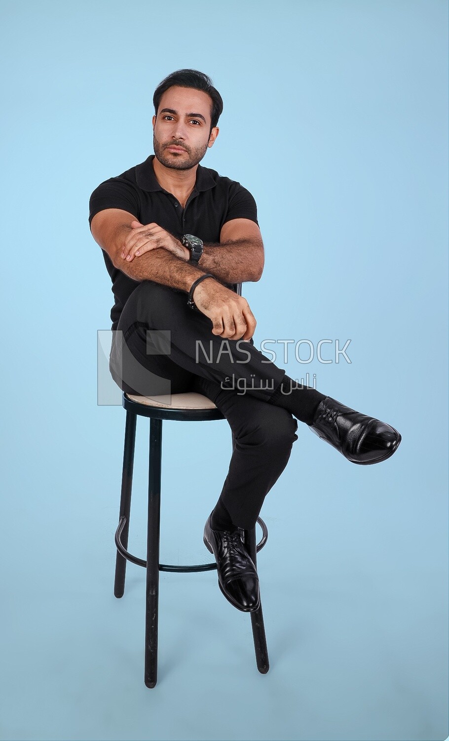 Photo of a Handsome man sitting on a chair and putting a leg on a leg, Smiling Man, Wearing Casual Clothes Posing In a Light Room Interior, Smiling At the Camera