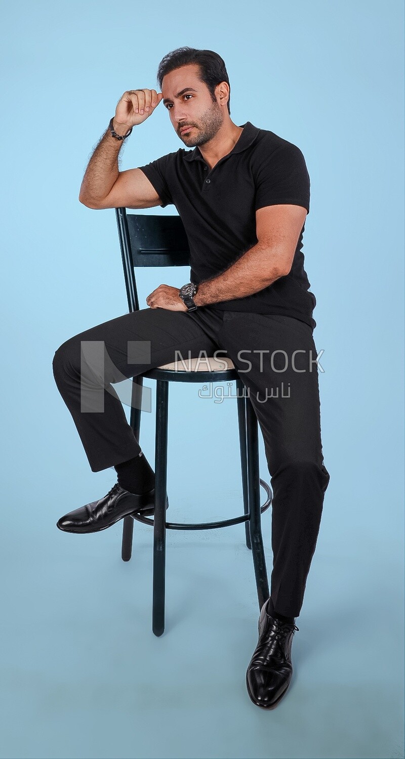 Photo Of a Handsome man sitting on the chair, Smiling Man, Wearing Casual Clothes Posing In a Light Room Interior, Smiling At the Camera