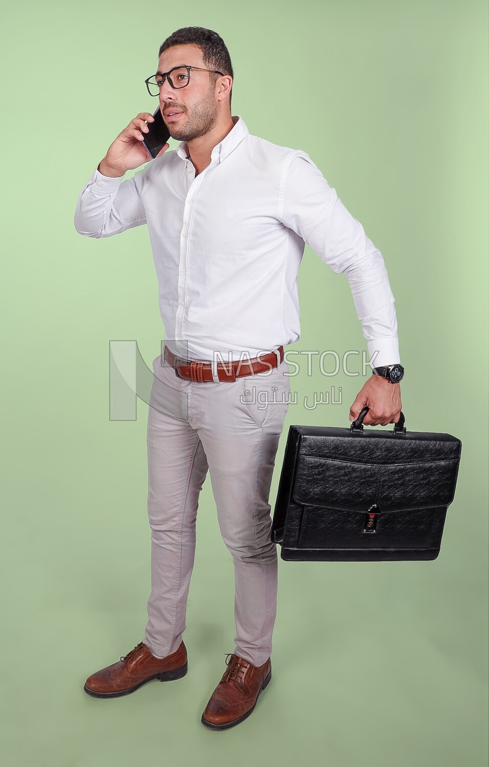 Photo of a handsome man wearing glasses and holding a leather bag and talking on a phone, business and partnership development, business meeting, model