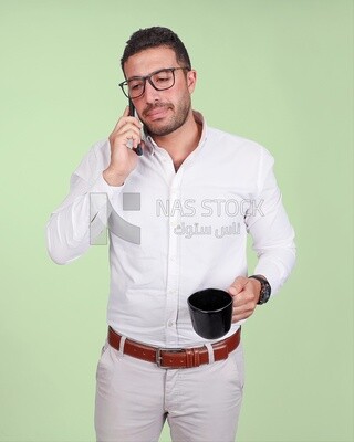 Photo of a handsome man wearing glasses standing talking on his phone and drinking coffee, business development and partnerships, business meeting, model