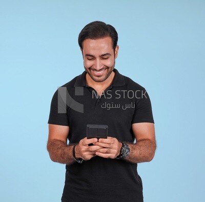 Photo Of a Handsome man Standing and holding his mobile, Smiling Man, Wearing Casual Clothes Posing In a Light Room Interior, Smiling At the Camera