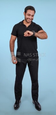 Portrait Of a Handsome man Standing and looking at his watch, Smiling Man, Wearing Casual Clothes Posing In a Light Room Interior, Smiling At the Camera