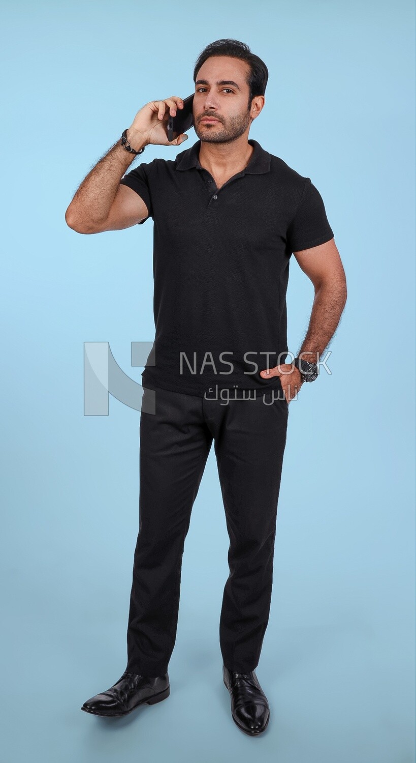 Photo Of a Handsome man Standing and talking in the mobile, Smiling Man, Wearing Casual Clothes Posing In a Light Room Interior, Smiling At the Camera