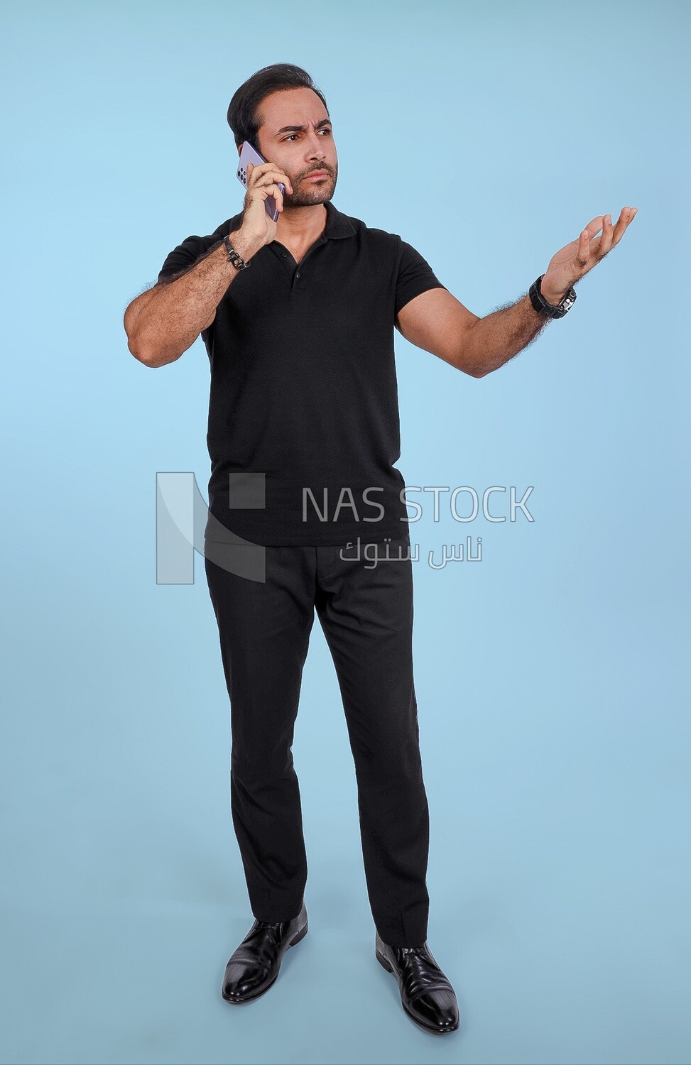 Portrait of a handsome man standing and talking to the mobile phone looking annoyed, man smiling, dressed in casual clothes in light room interior, smiling at camera