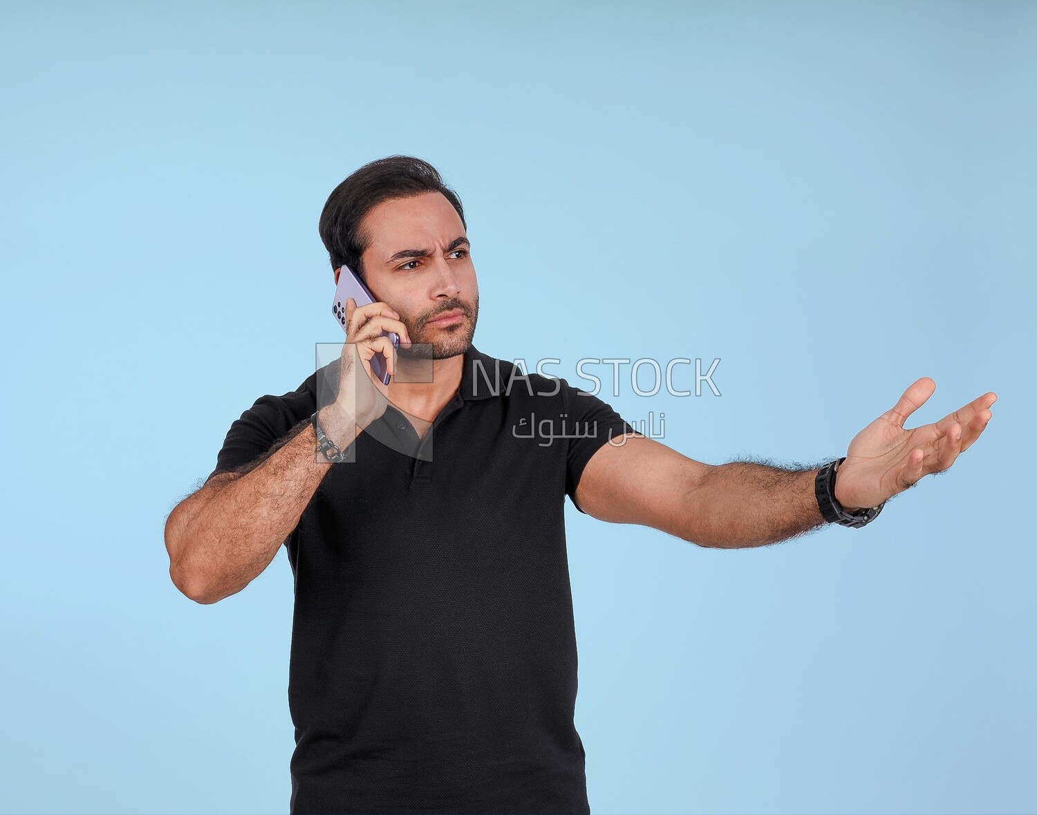 Portrait of a handsome man standing and talking to the mobile phone looking annoyed, man smiling, dressed in casual clothes in light room interior, smiling at camera