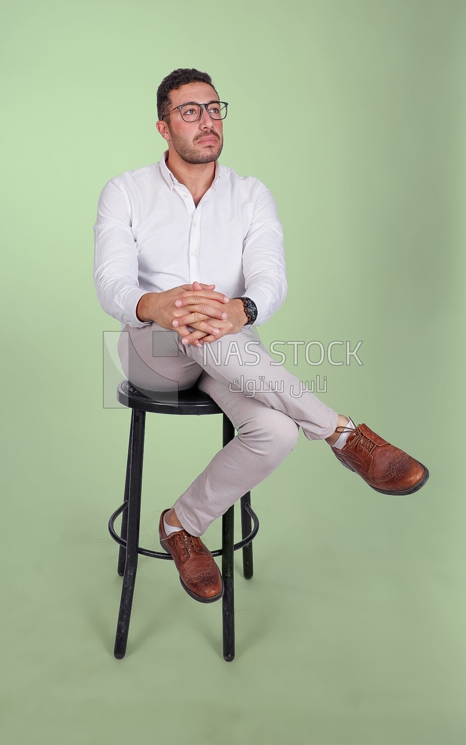 Photo of a Handsome man sitting on a chair and putting a leg on a leg, Smiling Man, Wearing Casual Clothes Posing In a Light Room Interior, Smiling At the Camera