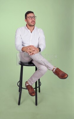 Photo of a Handsome man sitting on a chair and putting a leg on a leg, Smiling Man, Wearing Casual Clothes Posing In a Light Room Interior, Smiling At the Camera