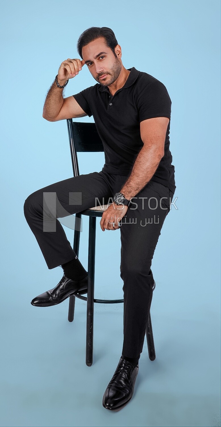 Photo Of a Handsome man sitting on the chair, Smiling Man, Wearing Casual Clothes Posing In a Light Room Interior, Smiling At the Camera