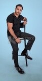 Photo Of a Handsome man sitting on the chair, Smiling Man, Wearing Casual Clothes Posing In a Light Room Interior, Smiling At the Camera