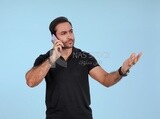 Portrait of a handsome man standing and talking to the mobile phone looking annoyed, man smiling, dressed in casual clothes in light room interior, smiling at camera