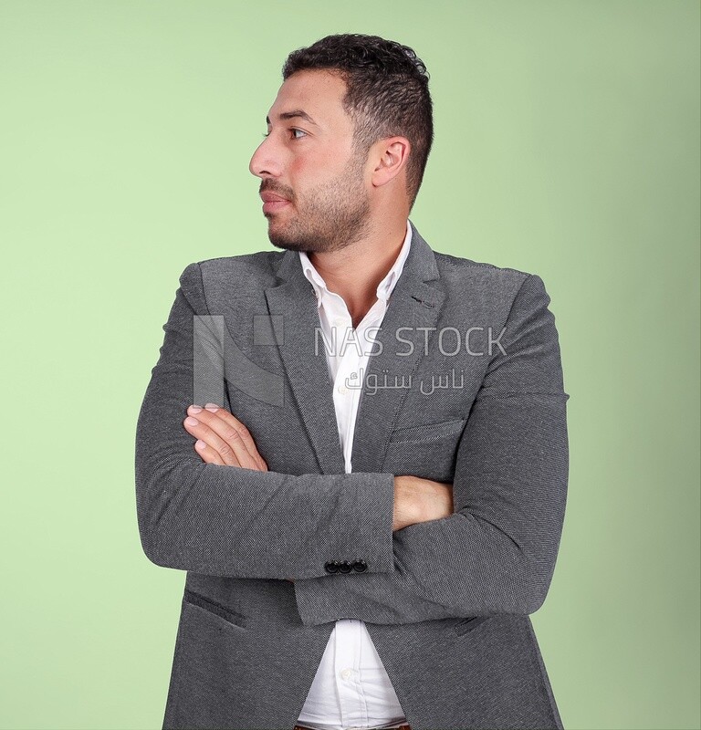 Photo of a man standing wearing a formal suit with crossed hands looking away, business development and partnerships, business meeting, Model