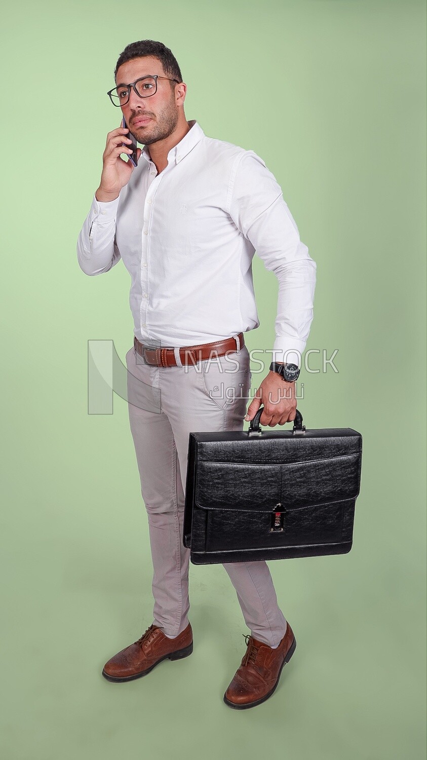 Photo of a handsome man wearing glasses and holding a leather bag and talking on a phone, business and partnership development, business meeting, model