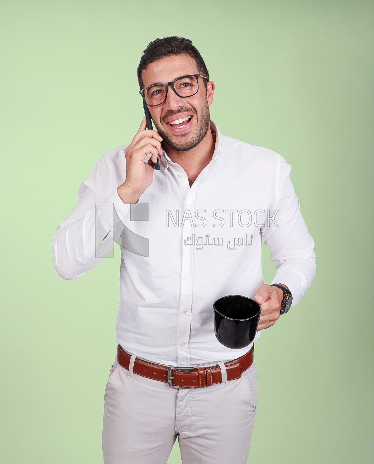 Photo of a handsome man wearing glasses standing talking on his phone and drinking coffee, business development and partnerships, business meeting, model