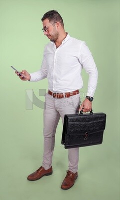 Photo of a handsome man wearing glasses looking at his phone and holding a leather bag, business and partnership development, business meeting, model