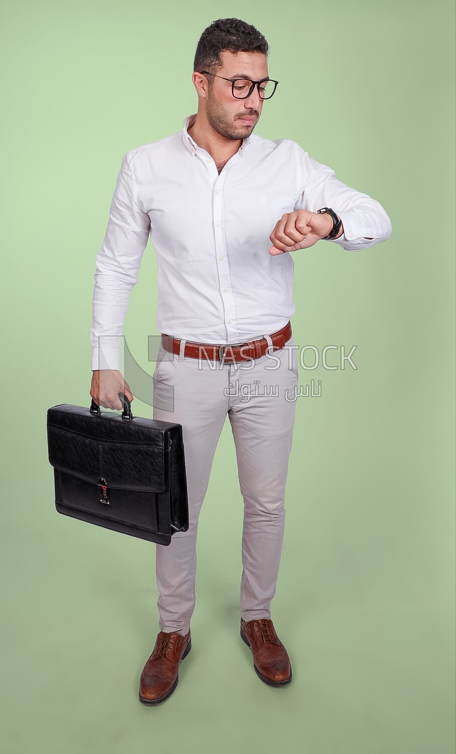Photo of a handsome man wearing glasses and holding a leather bag and looking at the watch, business and partnership development, business meeting, model