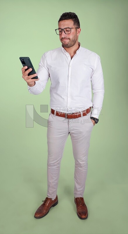 Photo of a handsome man wearing glasses standing looking at his phone, business development and partnerships, business meeting, model