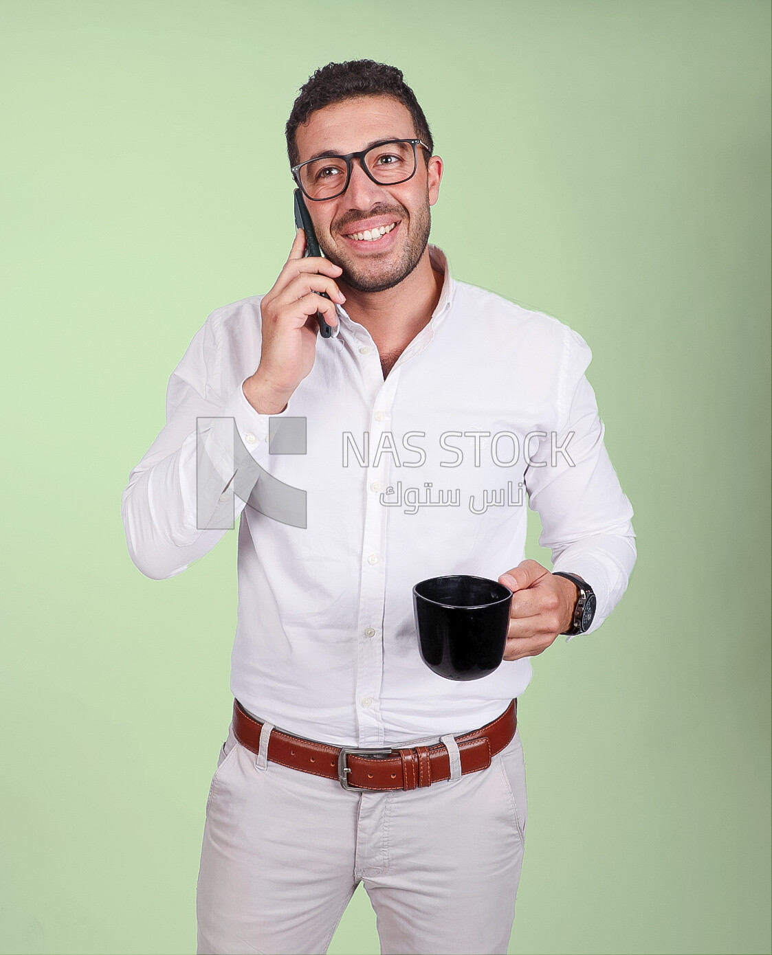 Photo of a handsome man wearing glasses standing talking on his phone and drinking coffee, business development and partnerships, business meeting, model