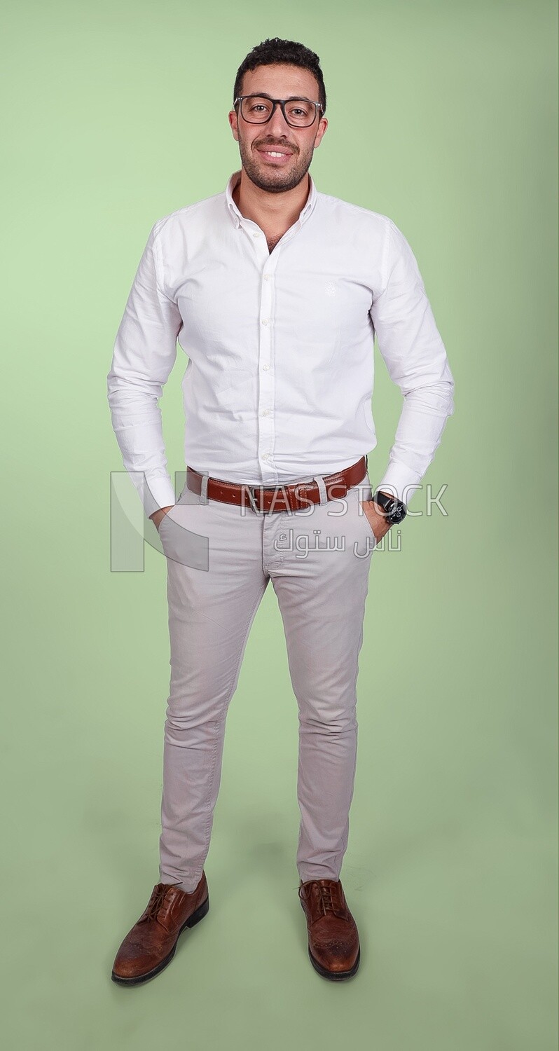 Photo of a handsome man standing and putting his hand in his pocket, a smiling man, dressed casually in an indoor light room, smiling at the camera, looking away