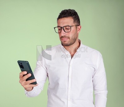 Photo of a handsome man wearing glasses standing and checking his phone, business development and partnerships, business meeting, model