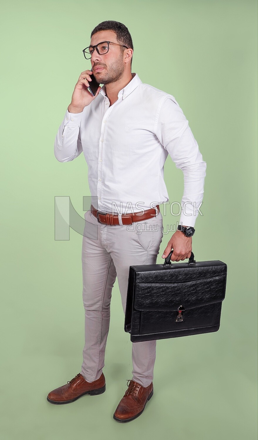Photo of a handsome man wearing glasses and holding a leather bag and talking on a phone, business and partnership development, business meeting, model
