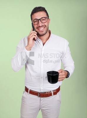 Photo of a handsome man wearing glasses standing talking on his phone and drinking coffee, business development and partnerships, business meeting, model