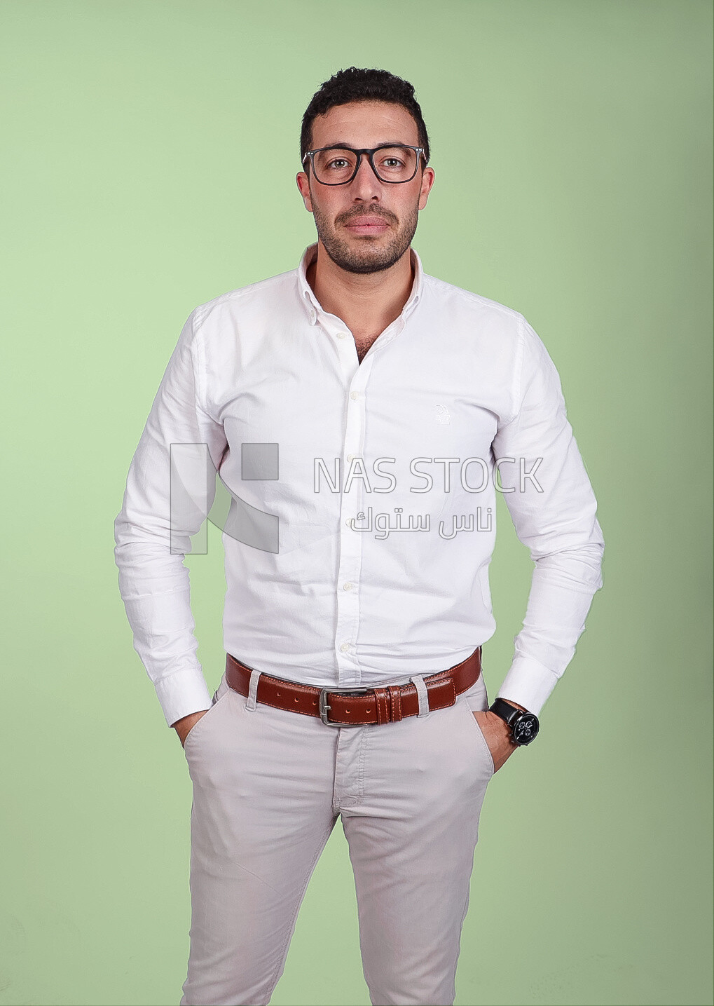 Photo of a handsome man standing and putting his hand in his pocket, a smiling man, dressed casually in an indoor light room, smiling at the camera, looking away