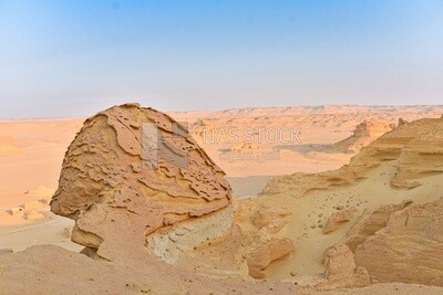 A scene of rock formations on a sandy mountain in the Wadi El Hitan desert in Egypt