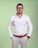 Photo of a handsome man standing and putting his hand in his pocket, a smiling man, dressed casually in an indoor light room, smiling at the camera, looking away