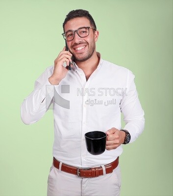 Photo of a handsome man wearing glasses standing talking on his phone and drinking coffee, business development and partnerships, business meeting, model