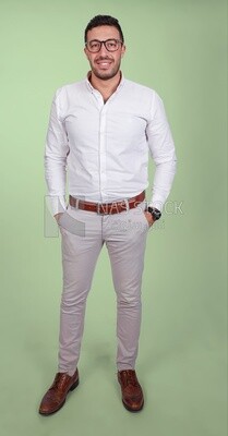 Photo of a handsome man standing and putting his hand in his pocket, a smiling man, dressed casually in an indoor light room, smiling at the camera, looking away