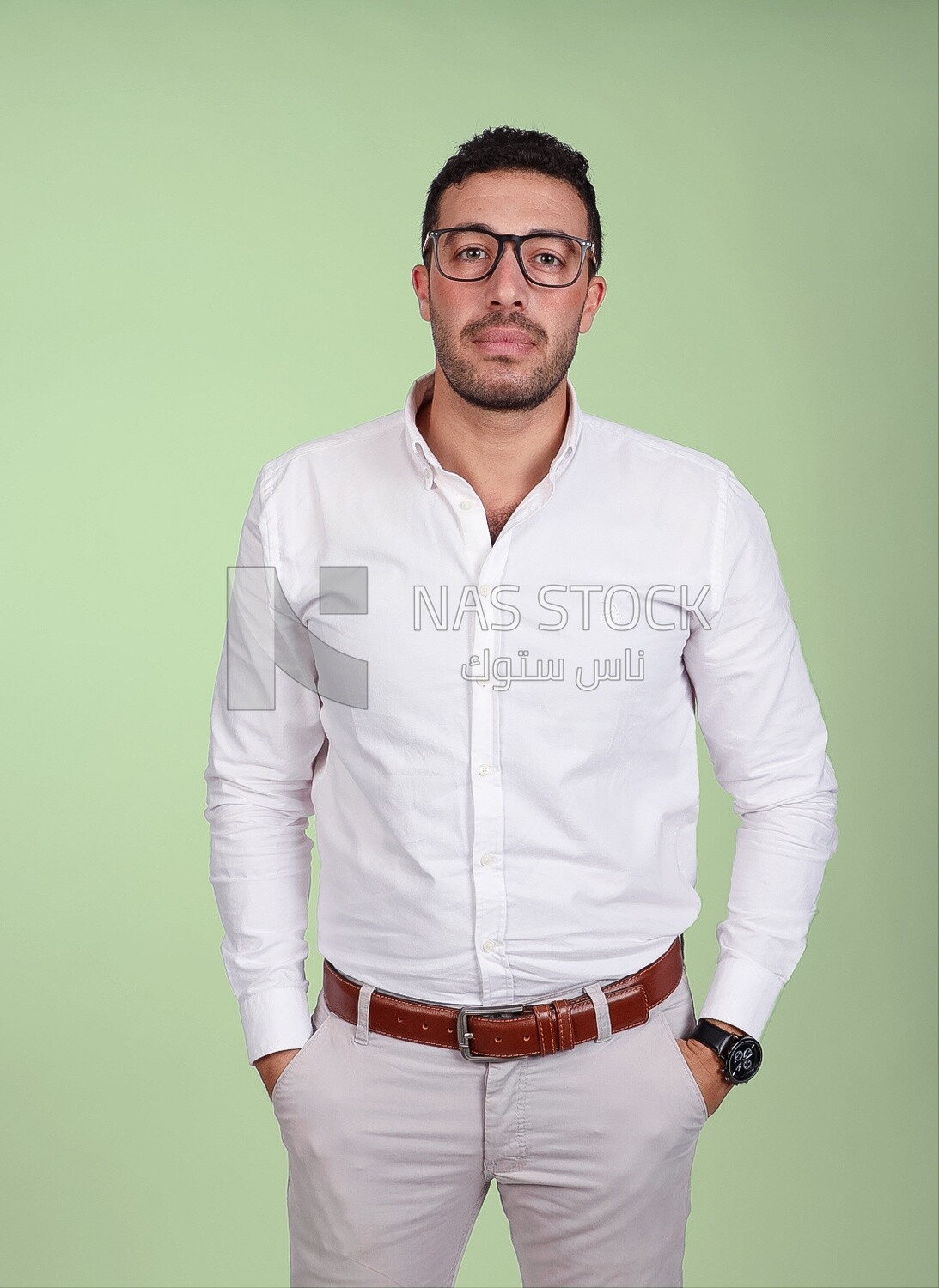 Photo of a handsome man standing and putting his hand in his pocket, a smiling man, dressed casually in an indoor light room, smiling at the camera, looking away