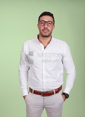 Photo of a handsome man standing and putting his hand in his pocket, a smiling man, dressed casually in an indoor light room, smiling at the camera, looking away