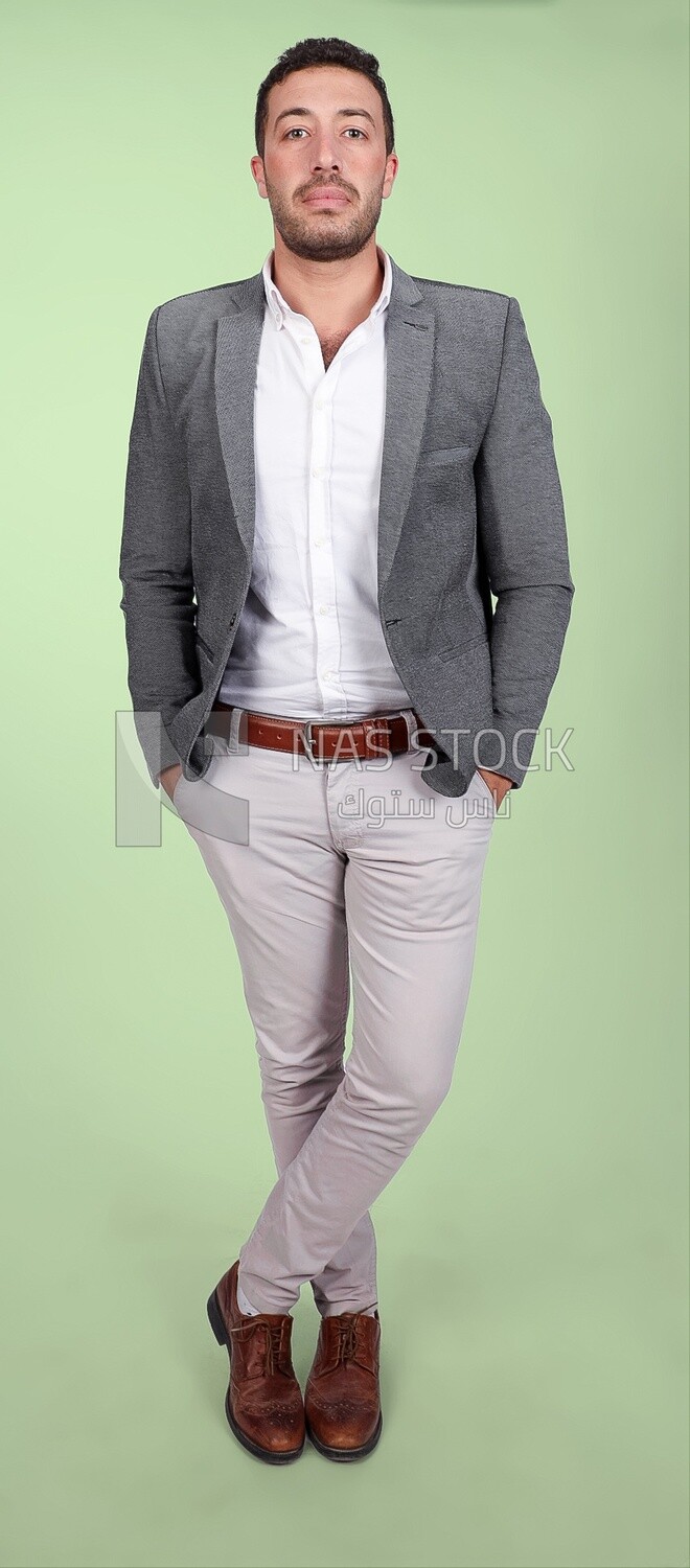 Photo of a handsome man standing and putting his hand in his pocket, a smiling man, dressed casually in an indoor light room, smiling at the camera, looking away