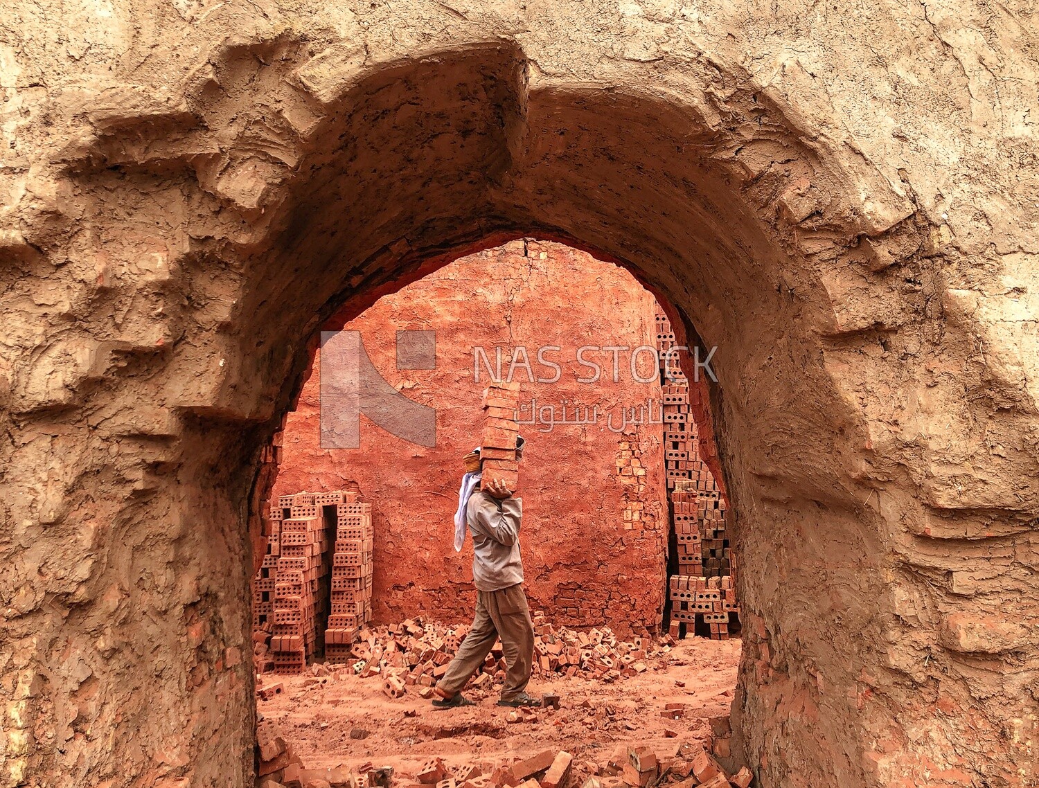 An Egyptian craftsman carrying a collection of red bricks