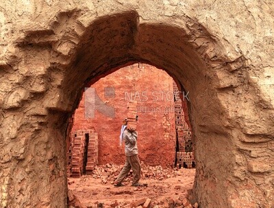 An Egyptian craftsman carrying a collection of red bricks