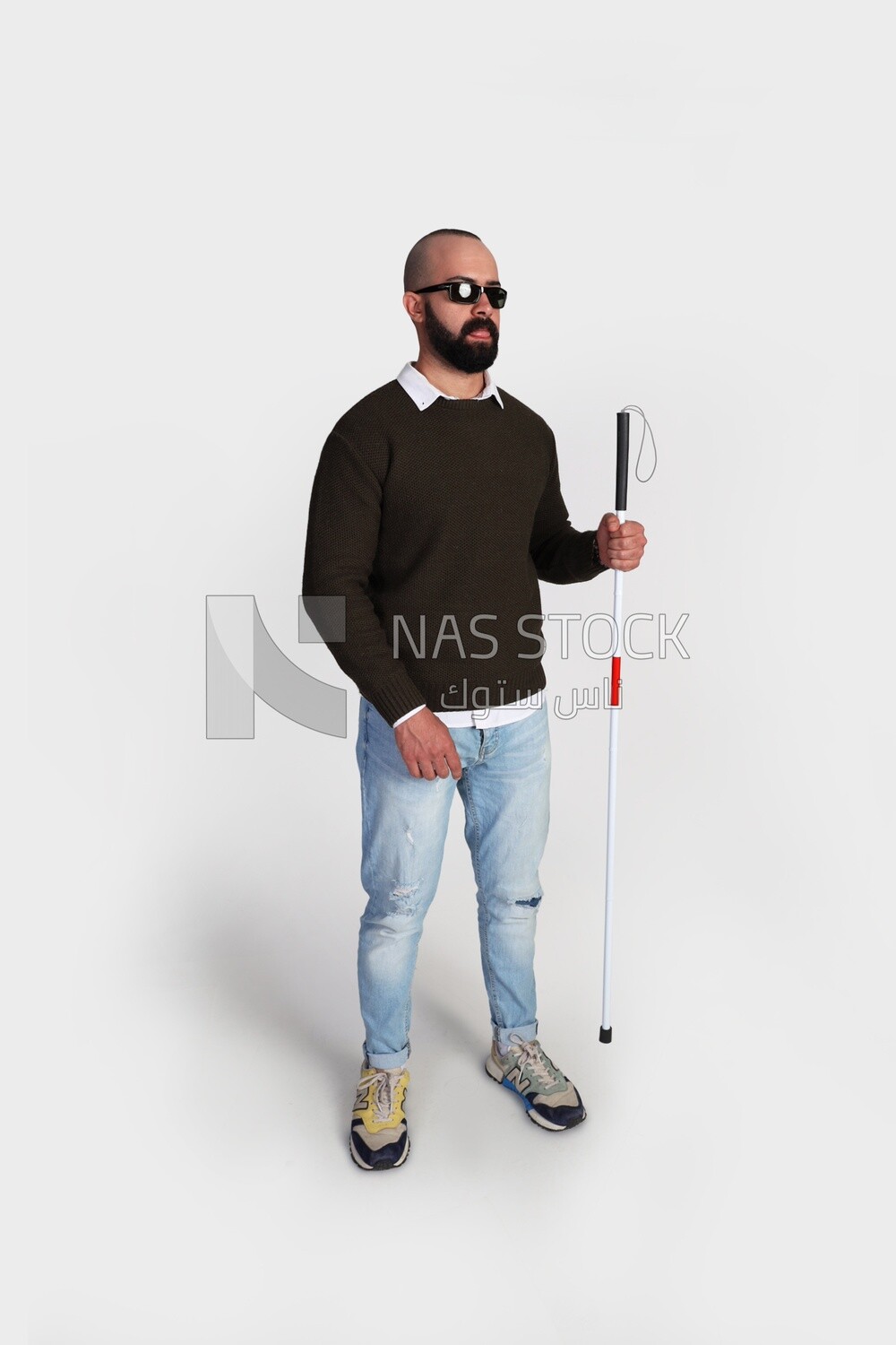 blind man standing wearing glasses and holding a walking stick