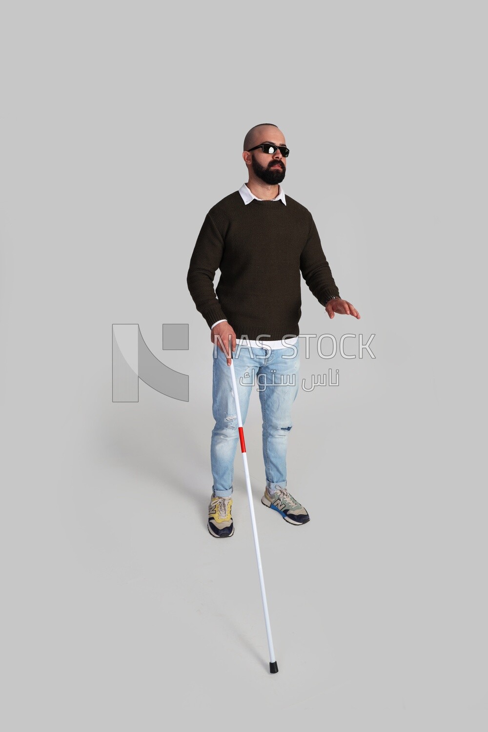 blind man standing wearing glasses and holding a walking stick