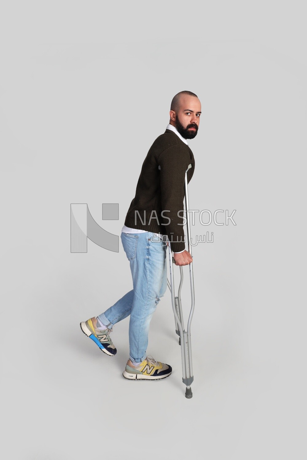 young man leaning on a crutch looking at the camera