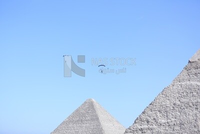 مشهد لأشخاص يطيرون في السماء وهم يرتدون المظلات امام الاهرامات المصرية