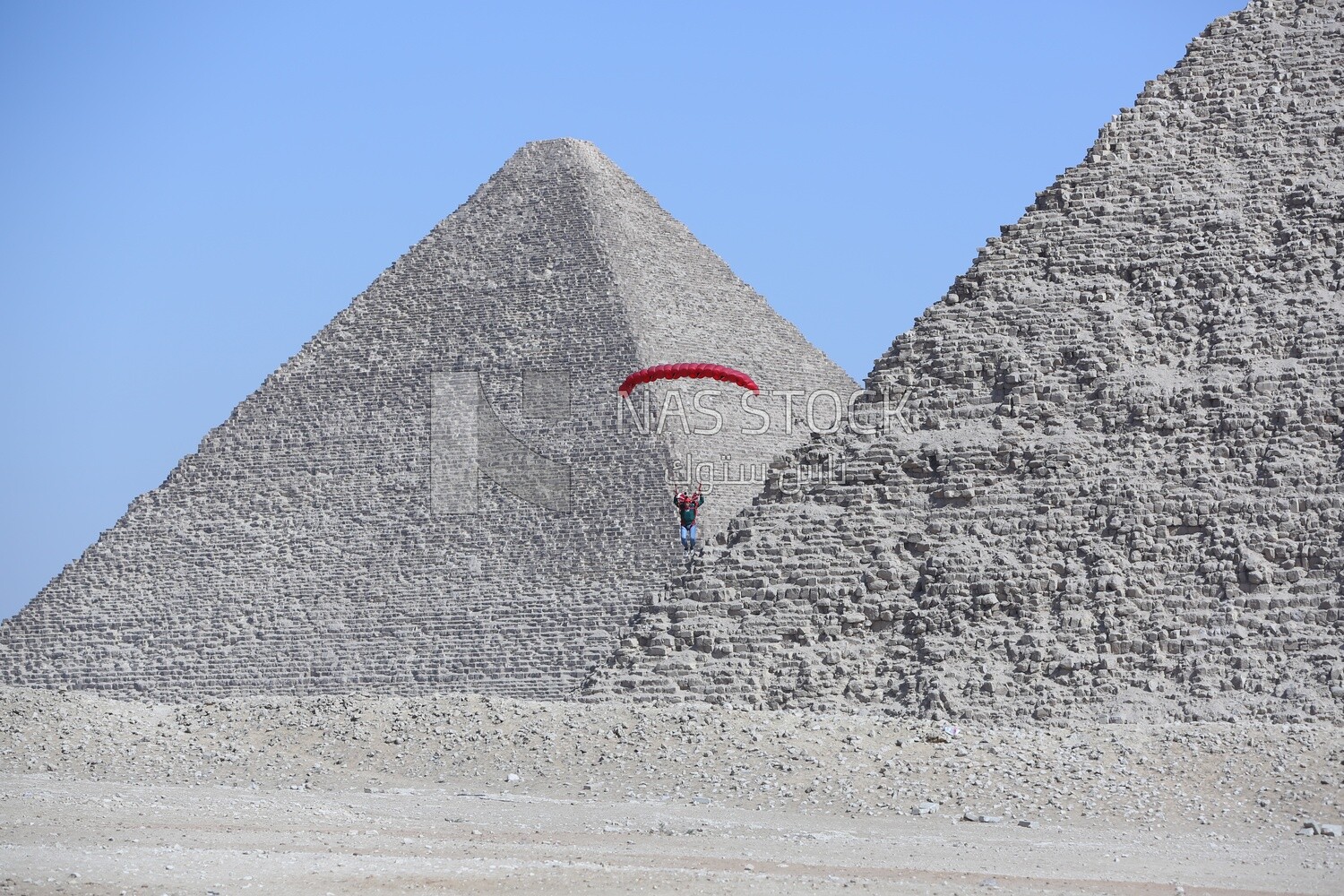 The scene of a person parachuting on the land of the pyramids in Egypt