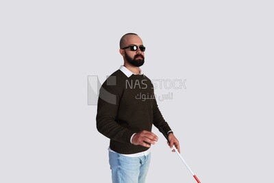 شاب  كفيف يرتدي نظارات و يمسك عصا للمشى