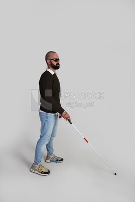 blind young man wearing glasses and holding a walking stick trying to figure out his way