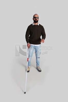 blind young man wearing glasses and holding a walking stick trying to figure out his way