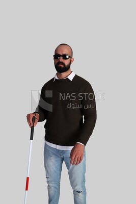 شاب كفيف يرتدي نظارات و يمسك عصا للمشى