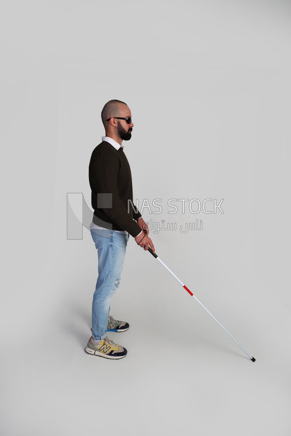 blind young man wearing glasses and holding a walking stick trying to figure out his way