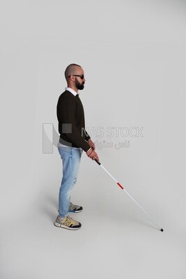 blind young man wearing glasses and holding a walking stick trying to figure out his way