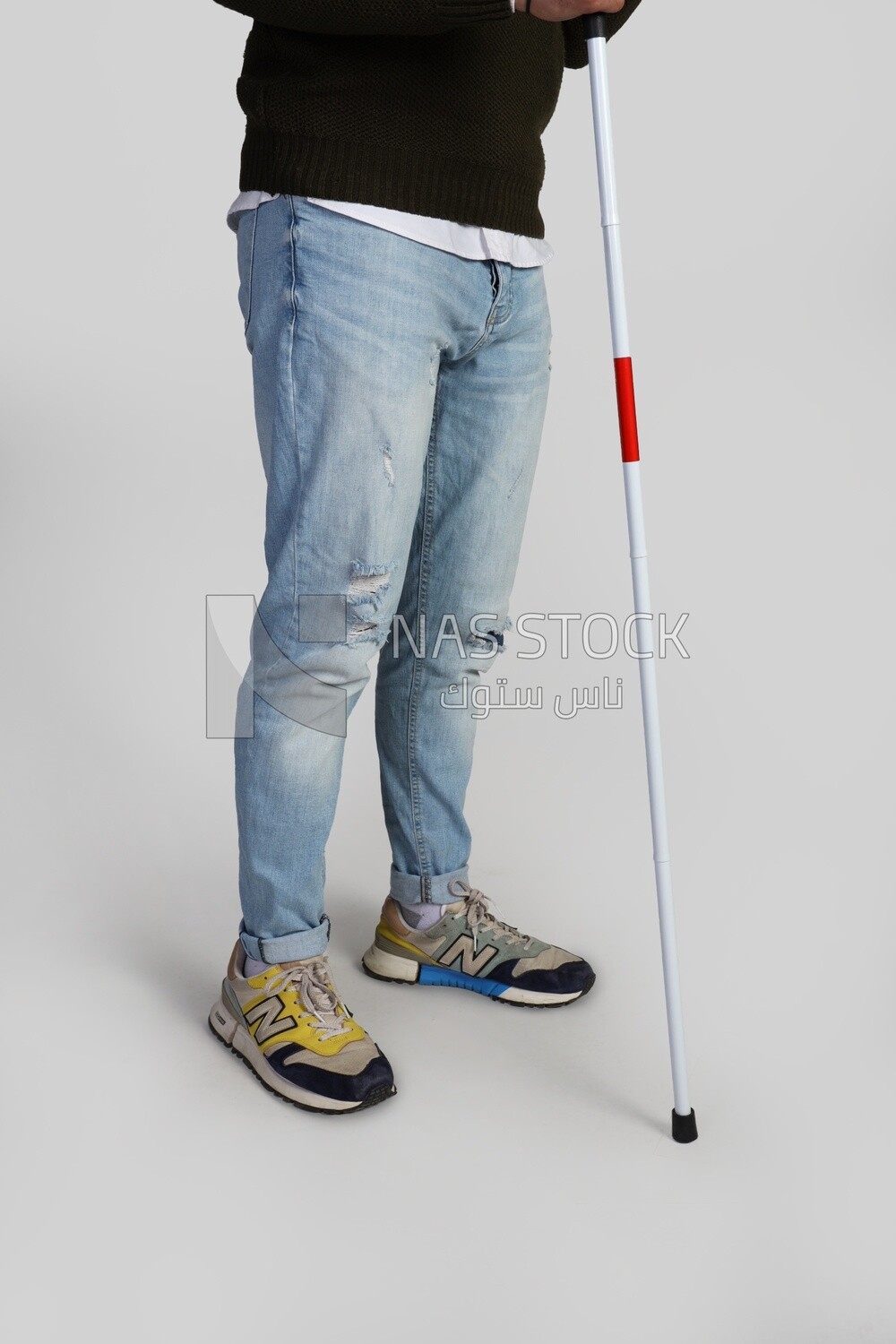 lower half of a blind man with a stick leaning on it
