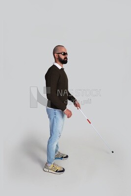 blind man standing wearing glasses and holding a walking stick